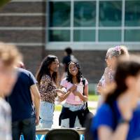 Students conversing outside on lawn